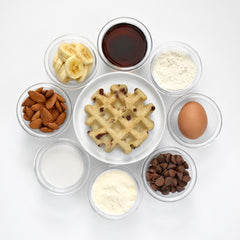 a chocolate chip waffle on a plate with various ingredients surrounding it